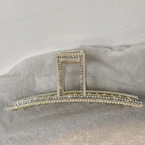 Détail de la grande pince à cheveux en métal doré avec perles et strass scintillants