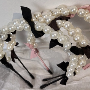 Detail of elegant pearl headband with silk bows on a textured white background