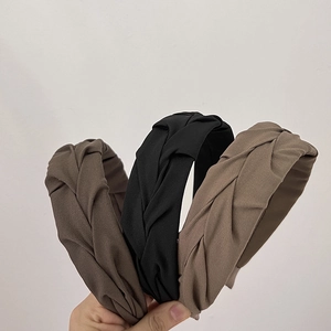 Close-up of three pleated twisted headbands in black, brown and khaki textured fabric