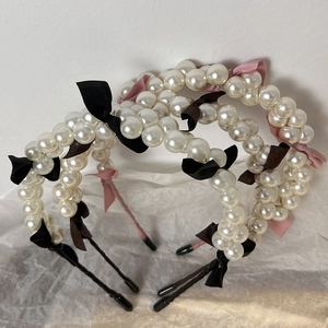 Detail of French style faux pearl headbands with satin bow accents in pink and black