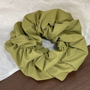 Detail view of olive green scrunchie fabric texture on a wooden table surface