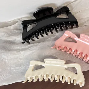 Detail showing oversized bow hair claws in black, pink and beige on textured paper