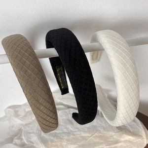 Close-up of three knitted diamond pattern sponge headbands in brown, black, and white