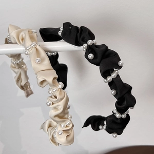 Detail von plissierten Satin-Stirnbändern mit weißen Perlen in Creme und Schwarz