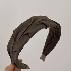 Detail of a dark brown pleated twist headband featuring soft textured ribbed fabric