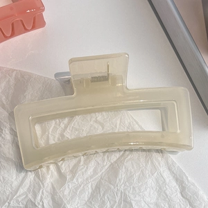 Detail view of a creamy white rectangular hair claw clip with a glossy translucent finish