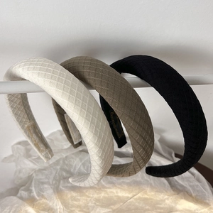 Detail of three padded headbands in white, brown and black with quilted lattice texture
