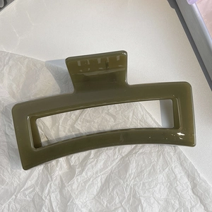 Detail of a large olive green rectangular hair claw clip with glossy resin finish