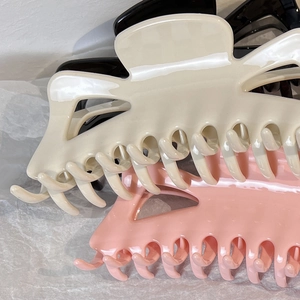 Close-up of large elegant bow hair claws in beige, pink and black on textured background