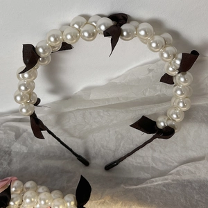 Detail of elegant pearl headband with black satin bows on textured background