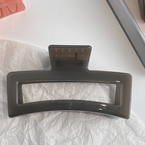 Close-up of translucent grey rectangular hair claw clip with geometric cutout design
