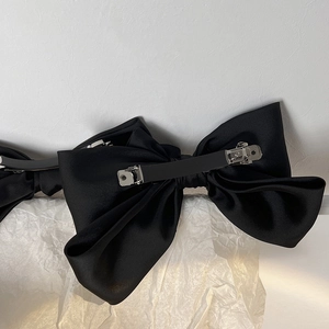 Close-up of the silver metal spring clip on the back of the black satin bow hairclip