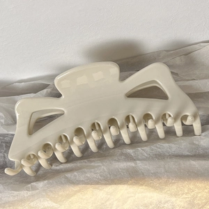 Macro shot of large cream white resin hair claw clip with glossy polished finish