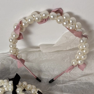 Detail of pearl headband with pink ribbon bow and black anti-slip protective covers