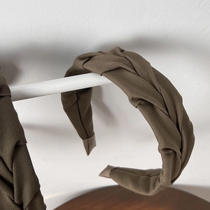 Detailed close-up of brown-green pleated fabric headband with premium woven texture