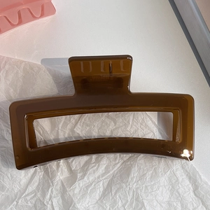 Macro detail of a large translucent amber rectangular hair claw clip with strong metal spring