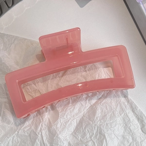 Macro detail of large translucent pink rectangular claw clip with metal spring