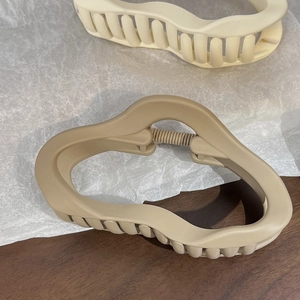 Detailansicht matter beige und khakifarbener Haarklammern in Wolkenform auf Holz