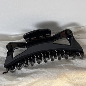 Detailed side view of large black glossy hair claw clip with geometric hollow cutouts