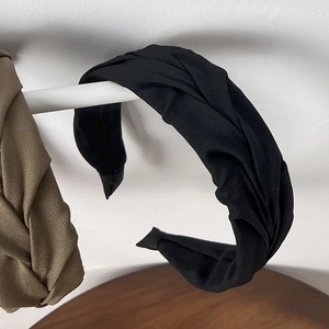 Detailed view of the twisted pleats on wide black and coffee knit headband headpieces