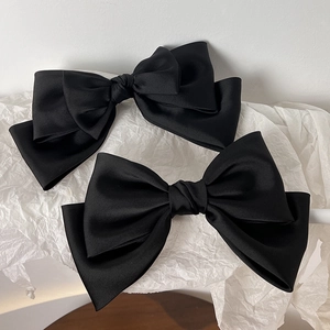Close-up of vintage black satin bow hair clips with elegant layered texture on white paper