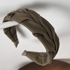 Close-up of olive green wide twisted headband with vintage knitted rib texture