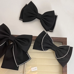 Set of three black bow hair clips with rhinestone edges on a vintage display tray