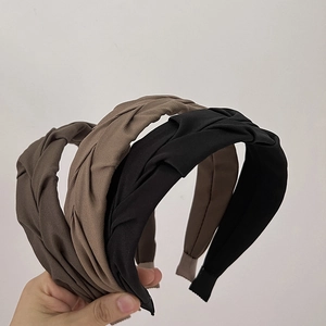 Close-up of twisted wide headbands in dark brown, light khaki, and black fabric