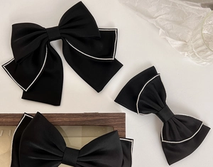 Detailed view of black satin bow hair clips with shimmering rhinestone edges