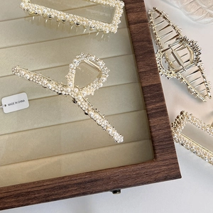 Detail showing elegant gold metal hair claws with white pearls in geometric shapes
