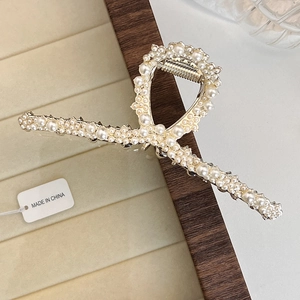 Macro detail of elegant large shark clip with faux pearls on silver metal alloy frame