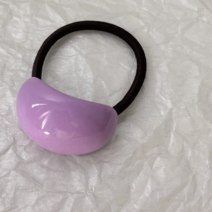 Dettaglio dell'elastico per capelli con perla in resina viola e fascia nera