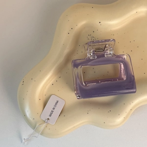 Detailed close-up of a purple translucent hollow square hair claw clip on a tray