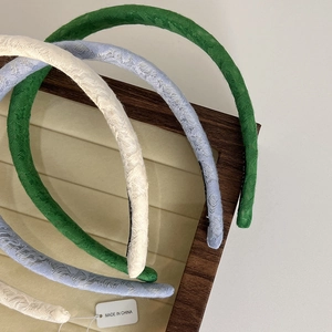 Close-up of textured fabric headbands in green and cream on a jewelry tray