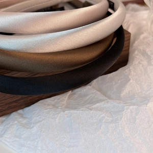 Close-up of four satin padded headbands in champagne, grey, olive green, and black colors