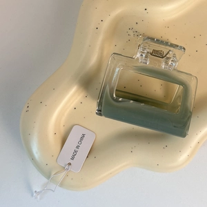 Detail view of square sage green and clear acrylic hair claw clip on ceramic tray