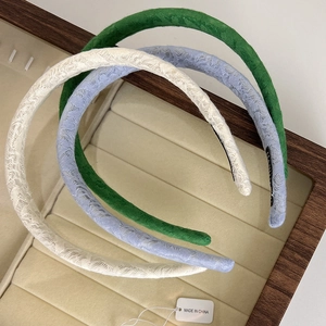 Detailed shot of three thin lace headbands in green, blue, and cream white on a tray
