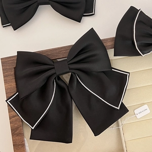 Close-up of black satin bow hair clips with silver rhinestones on display