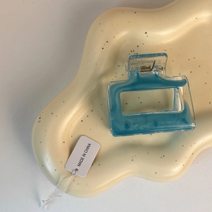 Detail of square hollow blue marble hair claw clip on cream wavy decorative plate