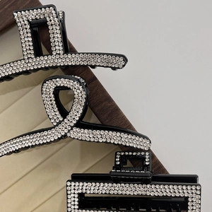 Detailed macro view of three black hair claws with luxury white rhinestone crystal pavé