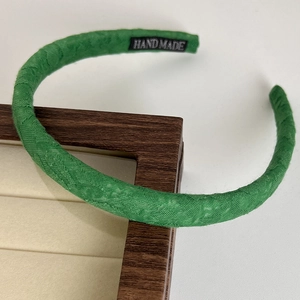 Detail of light green woven fabric headband featuring a hand made textile label inside