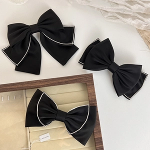 Three-piece black satin bow hair clips set with sparkling rhinestone edges on white background