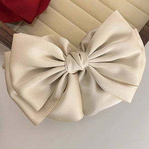 Detail of elegant champagne satin layered bow hair clip on a velvet display tray