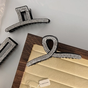 Detailed close-up of French-style black hair claws with elegant rhinestone encrusting
