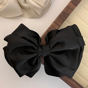 Close-up of elegant black multi-layer matte satin bow hair clip with smooth texture