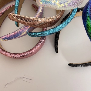 Flat lay of wide sequin headbands in various colors showing sparkling texture and detail