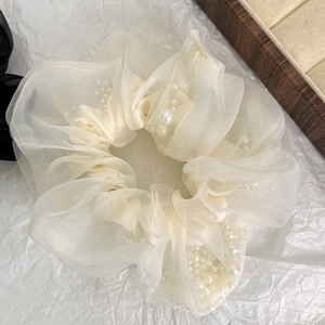 Detailopname van een gebroken witte organza scrunchie met parels op wit papier