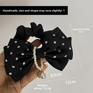 Vue détaillée d'un chouchou à nœud noir à pois élégant avec des perles suspendues