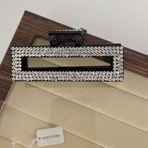 Detailed close-up of a rectangular black hair claw clip with sparkling rhinestones