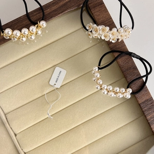 Détail de chouchous perles style français avec chaînettes dorées et fleurs blanches
